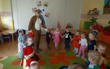 Sala zabaw-osoba dorosła z grupką dzieci stoją w k&oacute;łeczku w kolorowych bajkowych strojach.