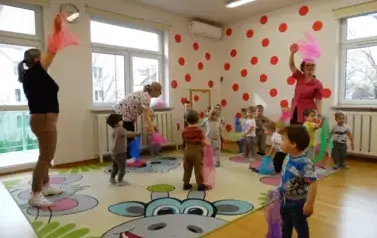 Grupa dzieci stoi na dywanie. W ręce trzymają kolorowe chusty.