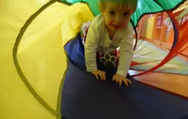 Sala zabaw-w kolorowym tunelu chłopiec opiera dłonie i kolanka o podłoże.