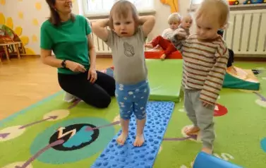 baw-na dywanie leży niebiesko-szary dywanik, po kt&oacute;rych chodzą dzieci.