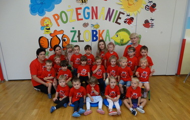 Grupa dzieci z opiekunami, w tle kolorowy napis "Pożegnanie żłobka"