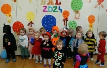 Sala zabaw-na pierwszym planie grupka dzieci w strojach postaci z bajek. W tle kolorowe balony i napis "BAL 2024"