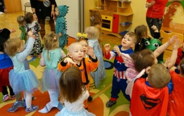 Sala zabaw-grupa dzieci w strojach postaci z bajek dotyka rączkami mydlanych baniek.