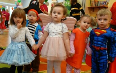 Sala zabaw-na pierwszym planie grupka dzieci w strojach postaci z bajek. W tle kolorowe balony.