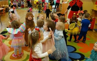 Sala zabaw-grupa dzieci w strojach postaci z bajek dotyka rączkami mydlanych baniek.