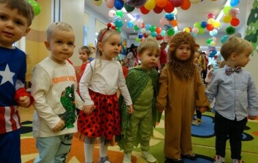 Sala zabaw-na pierwszym planie grupka dzieci w strojach postaci z bajek. W tle kolorowe balony.