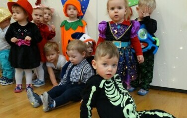 Sala zabaw-grupa dzieci w strojach postaci z bajek. W tle kolorowe balony.