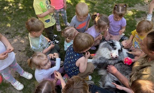 Zdjęcie przedstawia psa a wokół niego grupkę dzieci